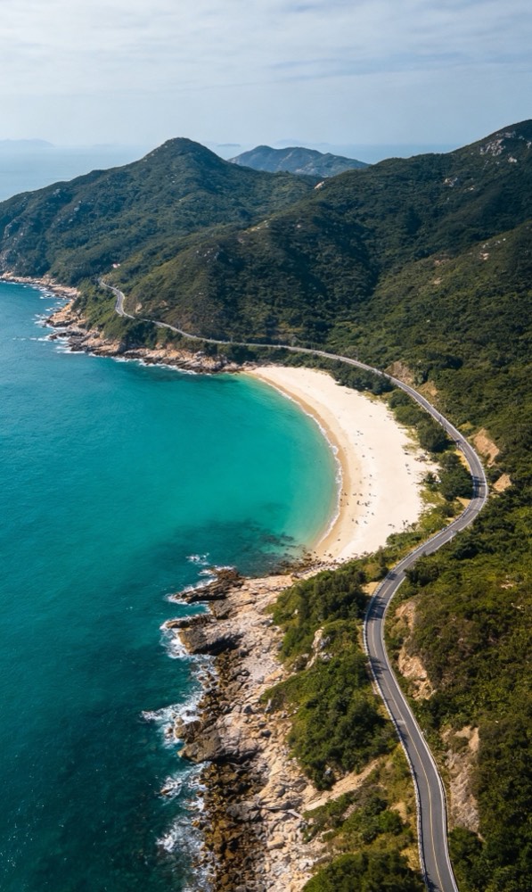Aerial view of the Yangmeikeng coast road curving around a white-sand bay